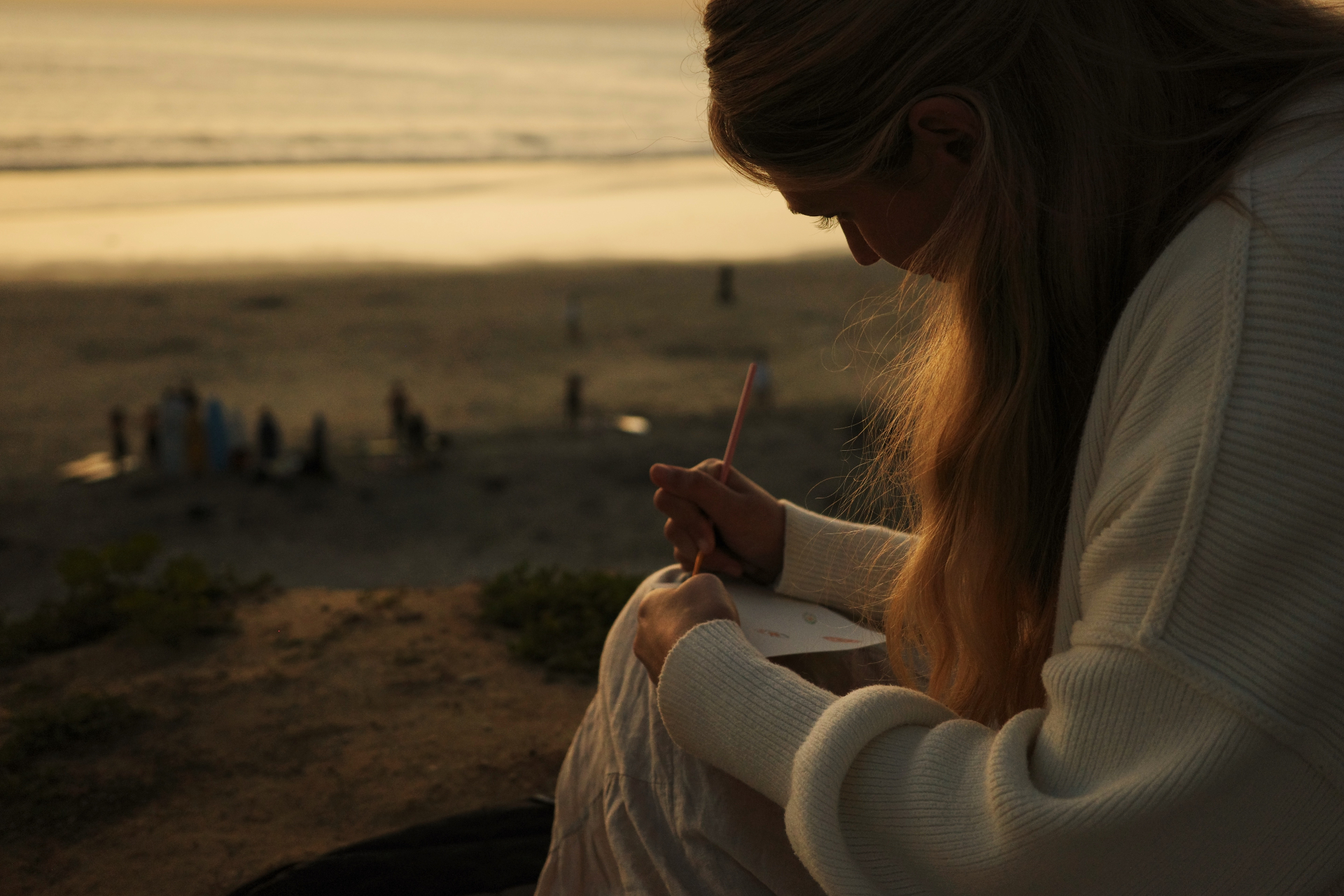 Girl sketching at the beach at golden hour